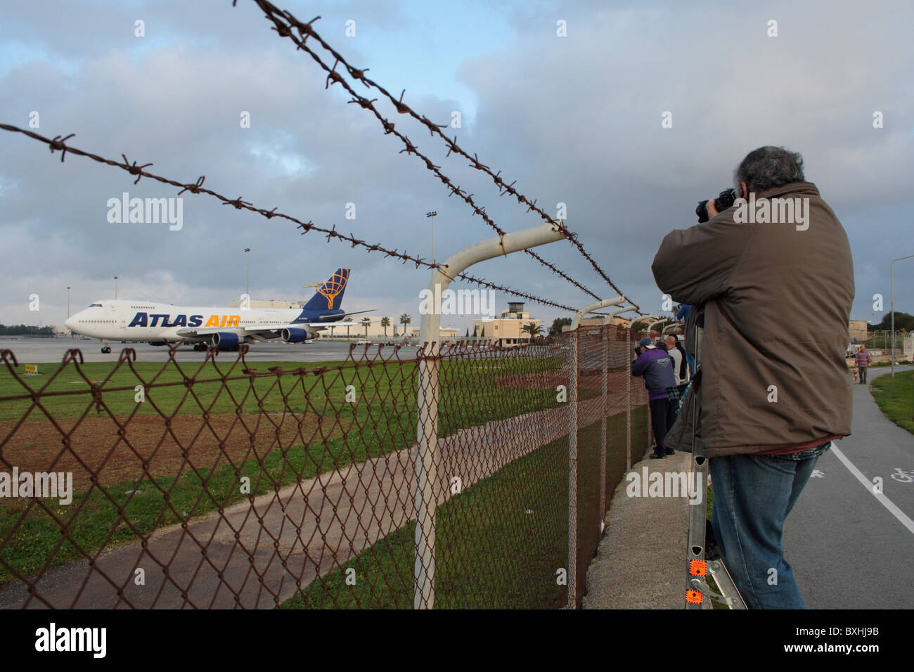 Planespotters tomando fotos de aviones procedentes de fuera de la valla perimetral de su aeropuerto local Foto de stock