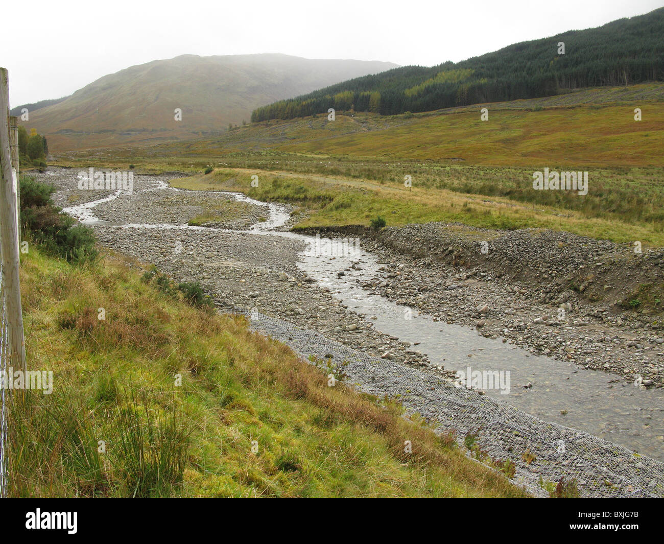 Río trenzadas con rock lleno de malla de acero de refuerzo gabion a sus bancos, cerca del puente de orchy, altiplano, Scotland, Reino Unido Foto de stock