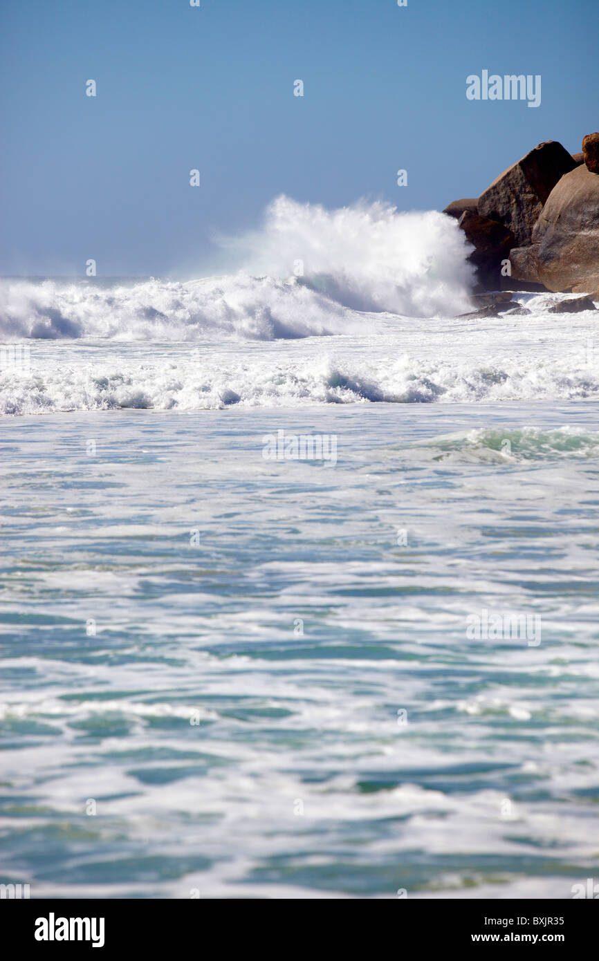 Olas rompiendo sobre las rocas rompiendo el mar azul océano rizado Foto de stock