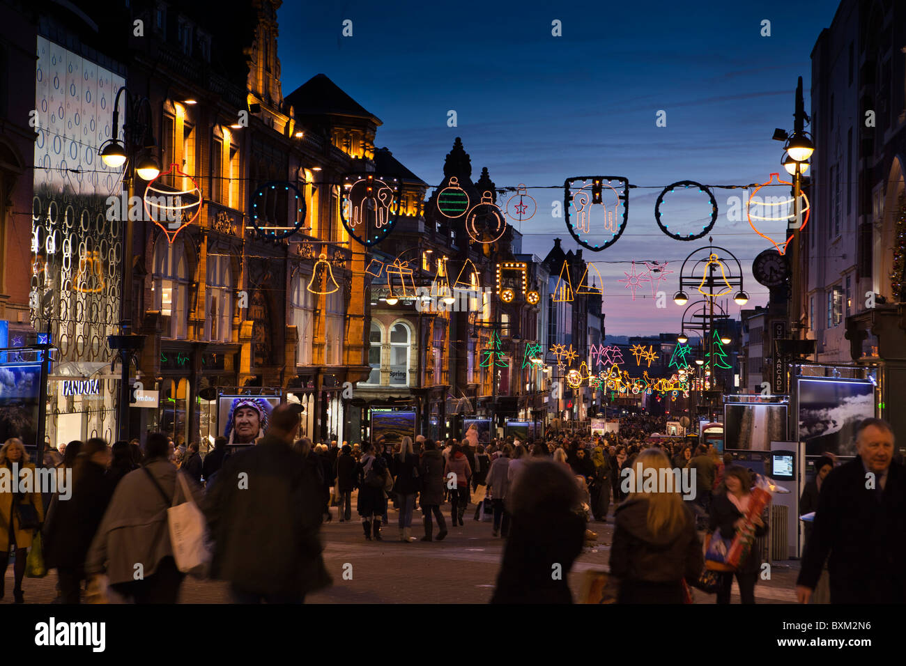 Reino Unido, Inglaterra, Yorkshire, Leeds, Briggate, compradores de último minuto por debajo de las luces de Navidad al atardecer Foto de stock