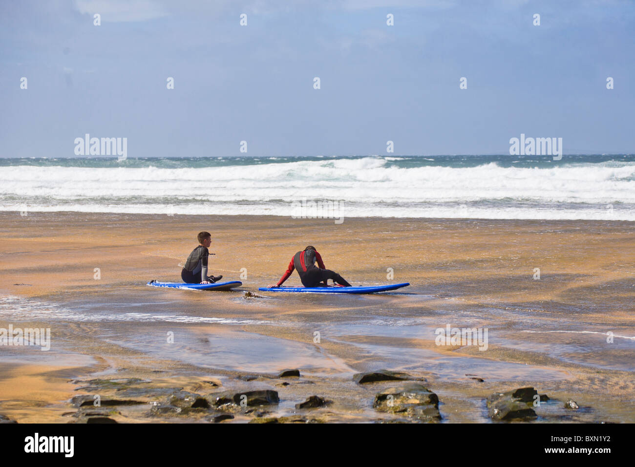 Dos surfistas sentado en la playa de Fanore, County Clare, Irlanda Foto de stock