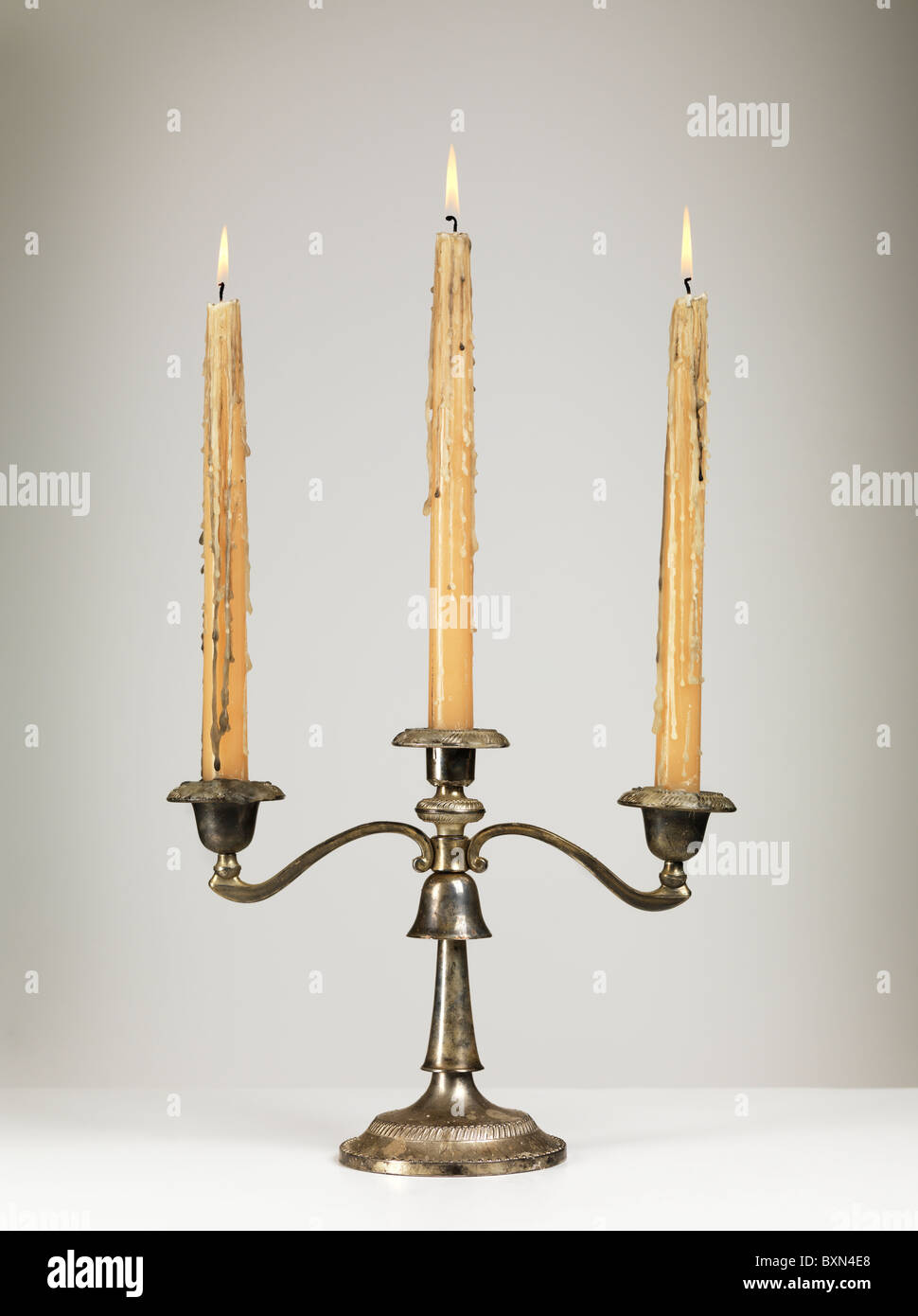 Plata antiguos candelabros portavelas triple aislado sobre fondo gris Foto de stock