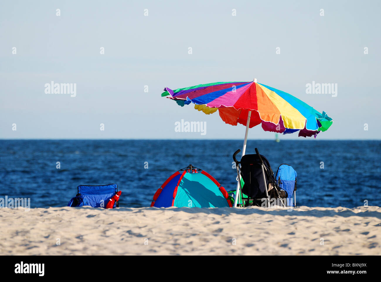 Colorido sol sombrilla, carpa y silla de playa, con el mar azul a la orilla  del mar en la época de vacaciones Fotografía de stock - Alamy