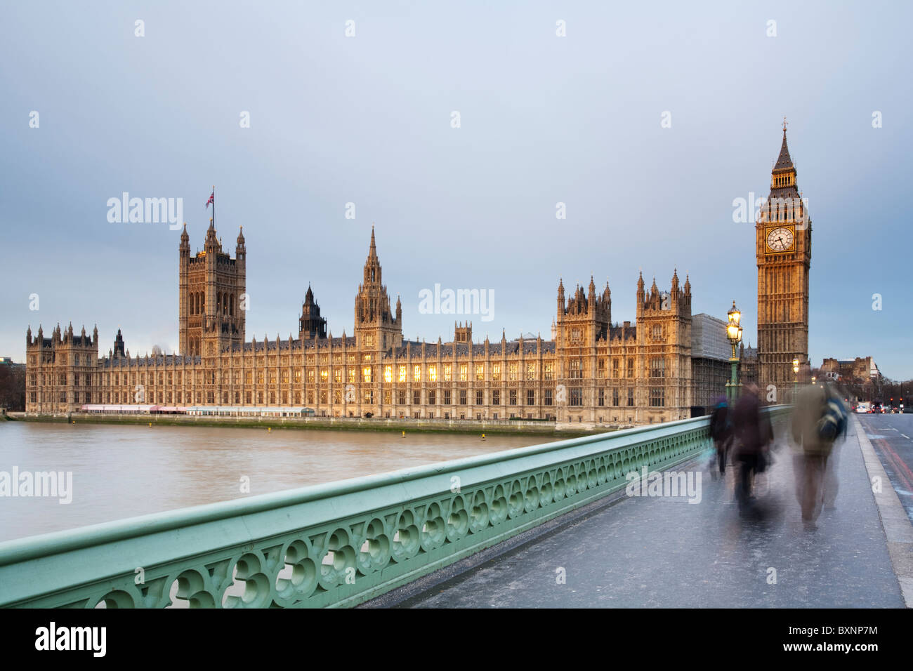 Temprano en la mañana los viajeros cruzando el puente de Westminster en un amanecer de invierno mirando hacia las Casas del Parlamento, London, UK Foto de stock