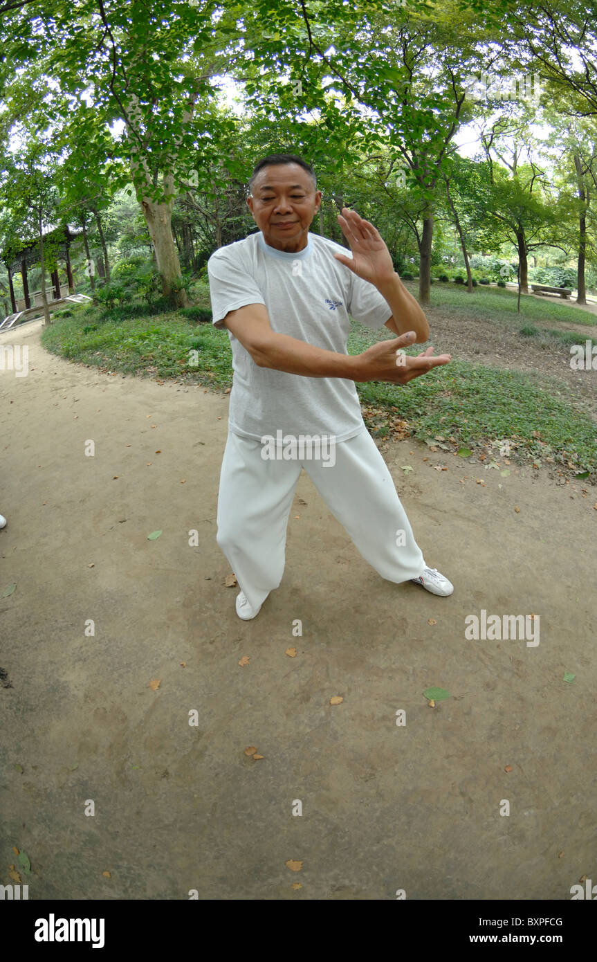 Un hombre vestido de blanco haciendo Tai chi chuan arte marcial afuera en esbelta West Lake Park Yangzhou Provincia de Jiangsu de China Foto de stock