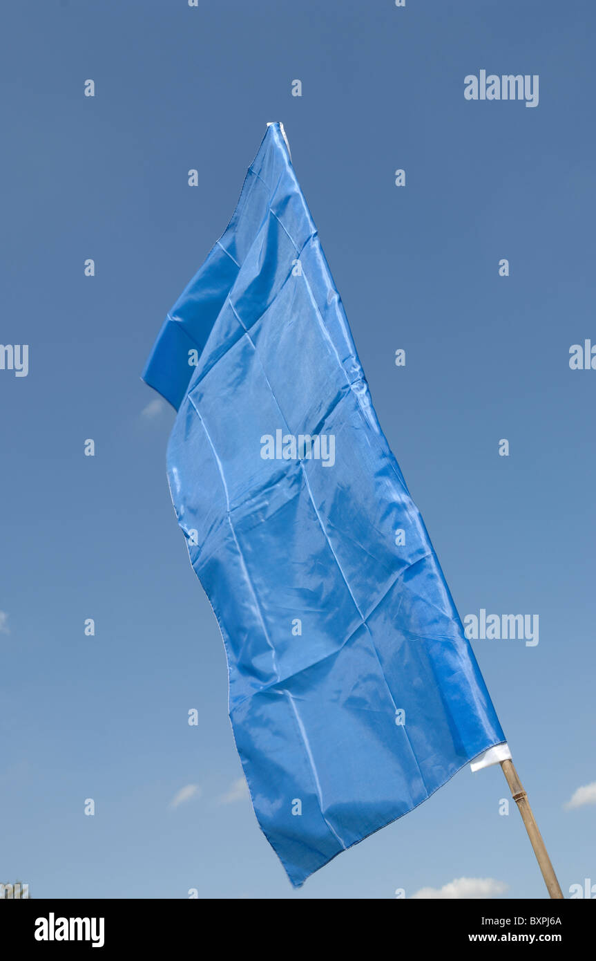 Una bandera de seda azul contra un cielo azul claro Foto de stock