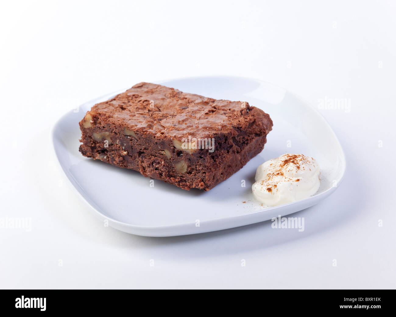 Pastel Brownie de chocolate servido en un plato con crema agria Foto de stock