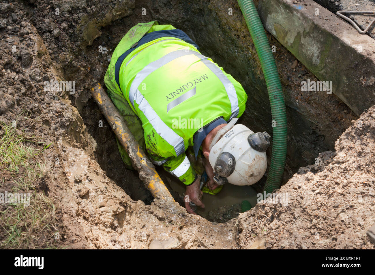 Trabajador de mayo GURNEY reparar una fuga en el tubo de alimentación de agua corriente Foto de stock