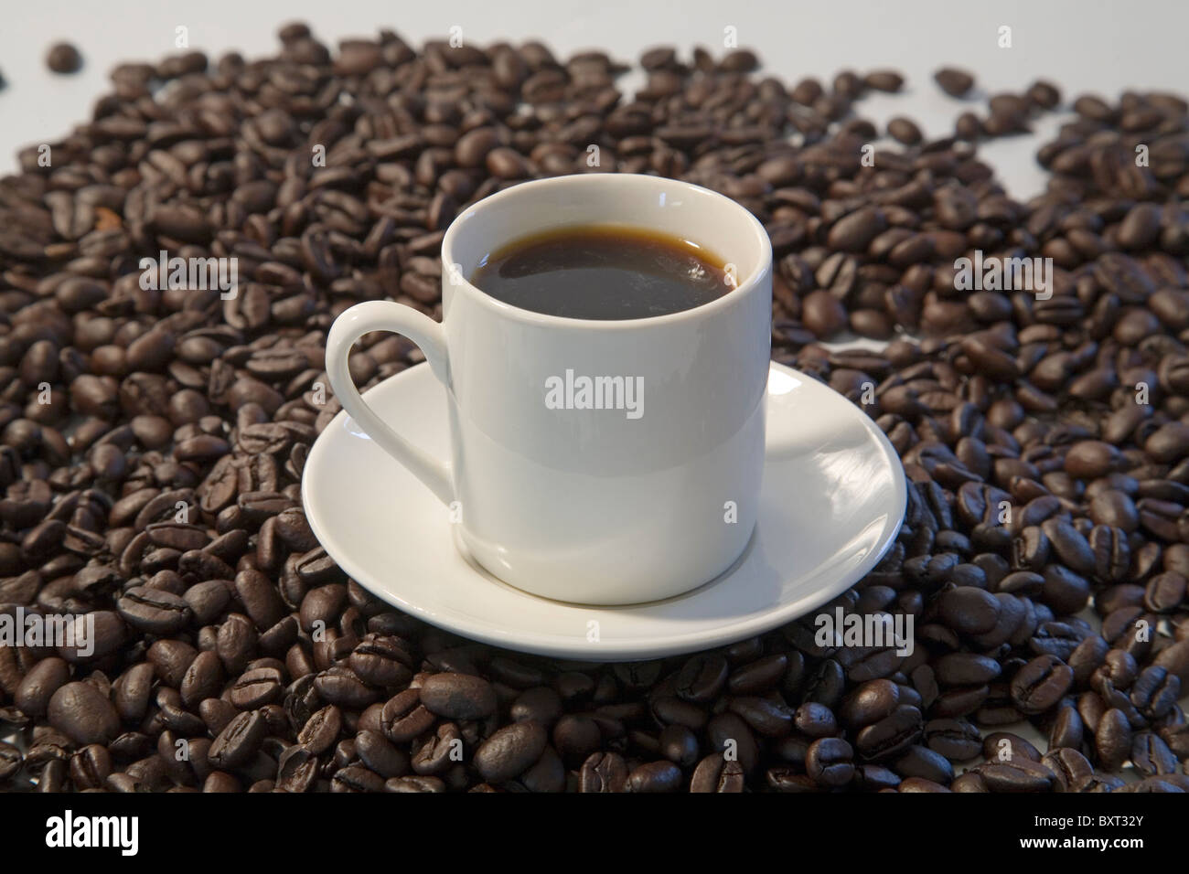 Una taza de café con granos de café expreso tostado oscuro Foto de stock
