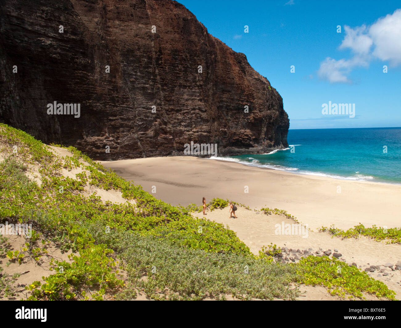 Las mujeres caminatas en la arena en Honopu beach, Costa Na Pali, Kauai Foto de stock