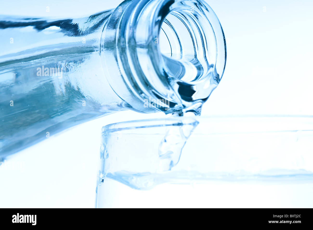 Vierte el agua en botella de vidrio Foto de stock