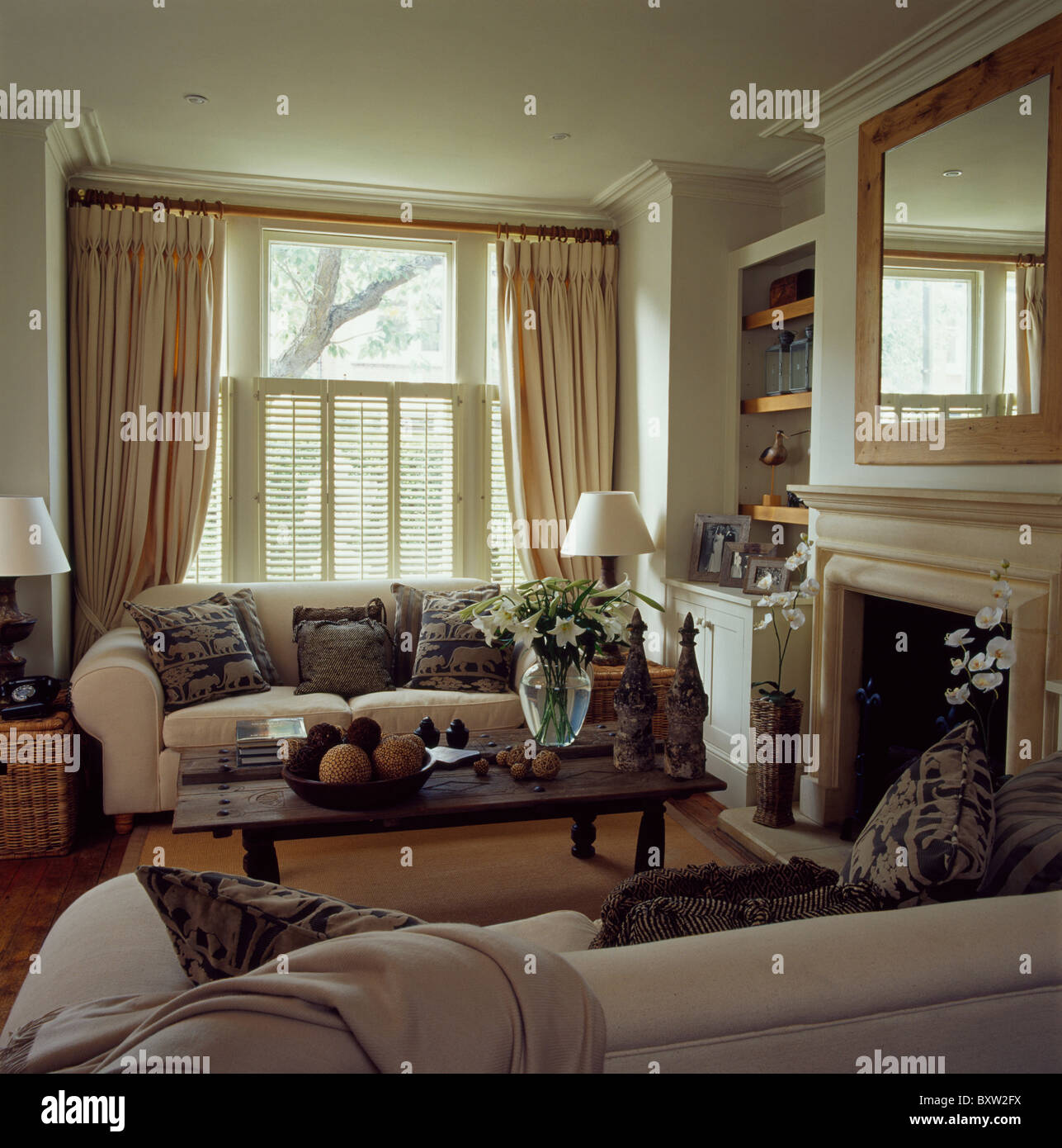 Sofás de color crema en la casa salón con crema de cortinas y persianas de  madera en la ventana Fotografía de stock - Alamy