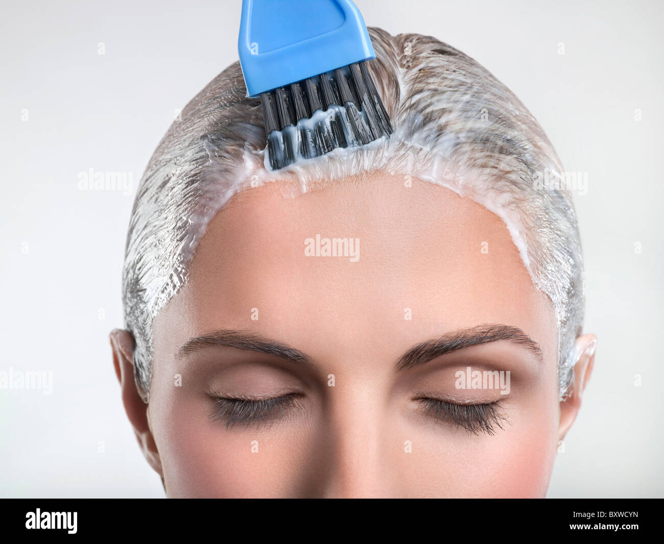 Mujer joven de aplicar el color del cabello Foto de stock