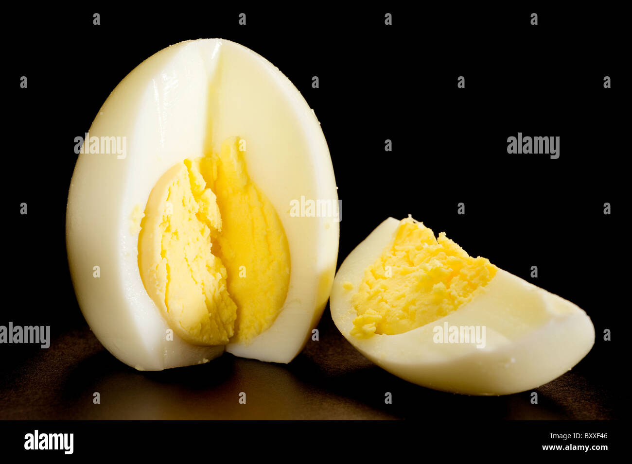 Huevos cocidos cortados en la mitad aislado sobre fondo negro Foto de stock