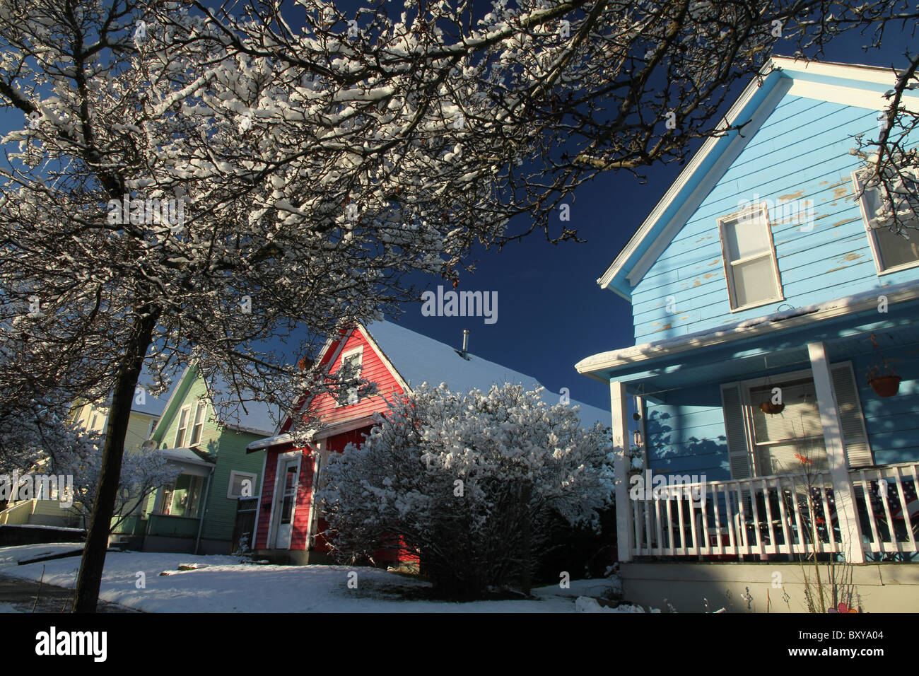 Cuatro casas; amarillo, verde, rojo y azul en la nieve en Bellingham, WA, EE.UU. Foto de stock