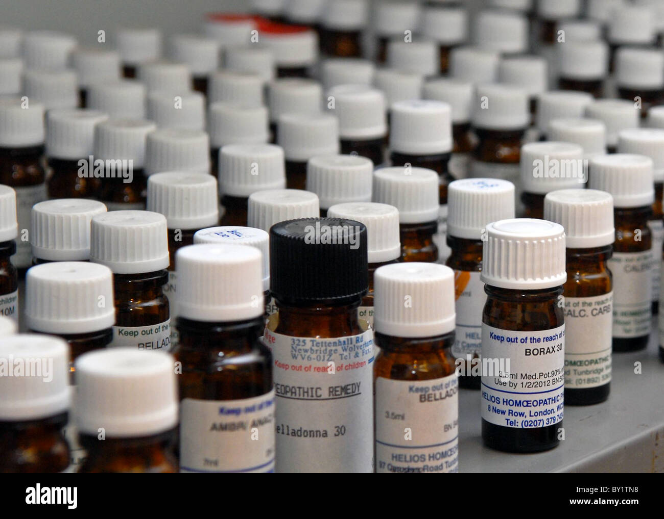 Filas de brown remedio homeopático botellas alineadas en un estante Foto de stock