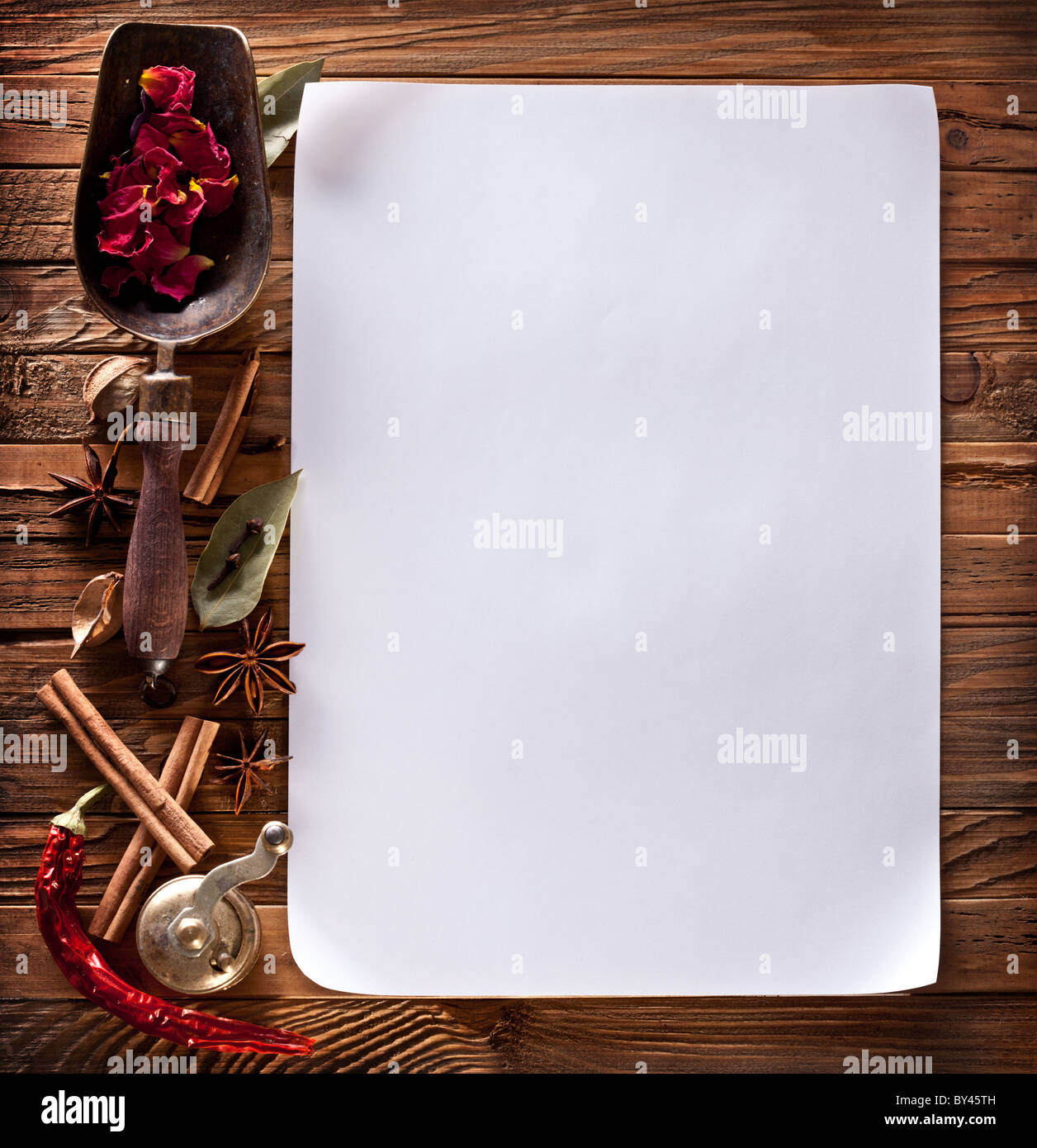 Imagen de papel blanco con especias sobre una superficie de madera Foto de stock