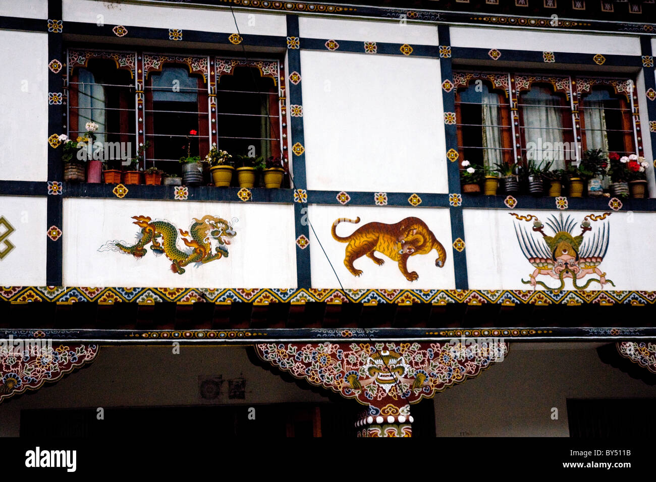 Obras de arte coloridas en el típico estilo Budista adorna un edificio tradicional que está en paro, Bhután Foto de stock