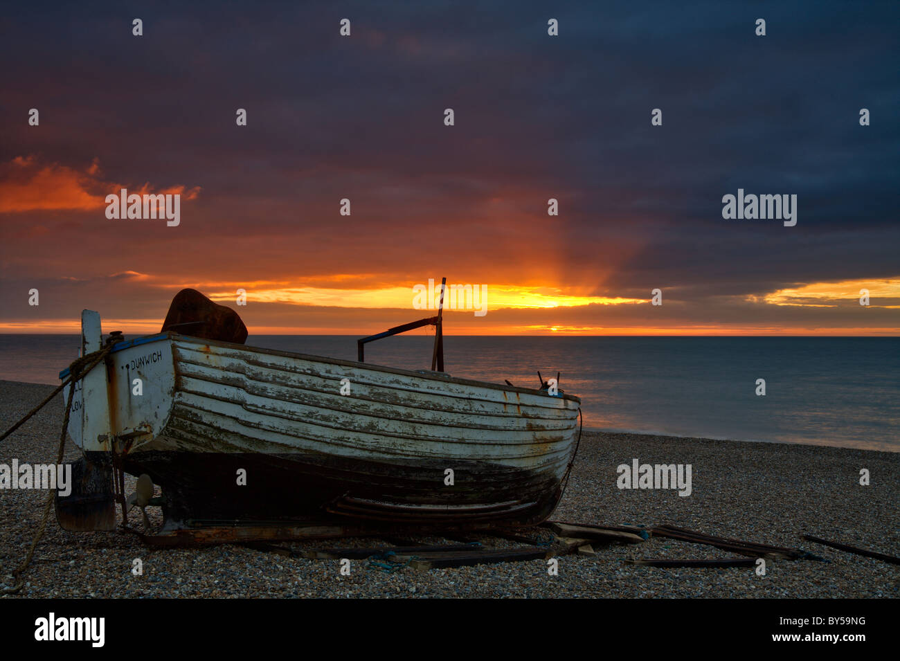 Dunwich Sunrise Beach y Suffolk tradicional barco pesquero en la costa Foto de stock