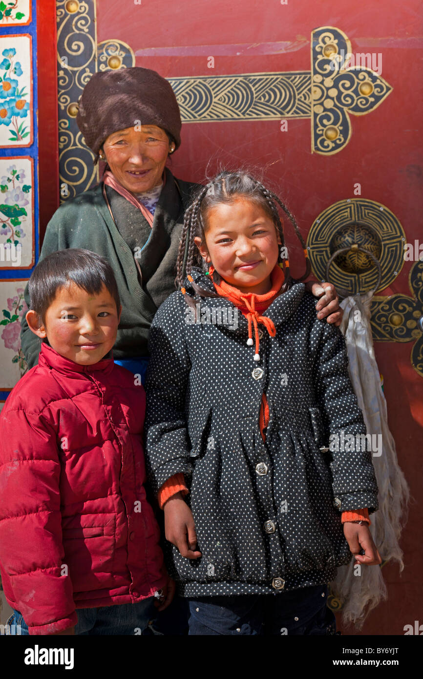 Mujer tibetana chico y chica delante de la entrada a la casa en la aldea tibetana en el camino desde el aeropuerto hasta Lhasa Lhasa (Tíbet). JMH4429 Foto de stock