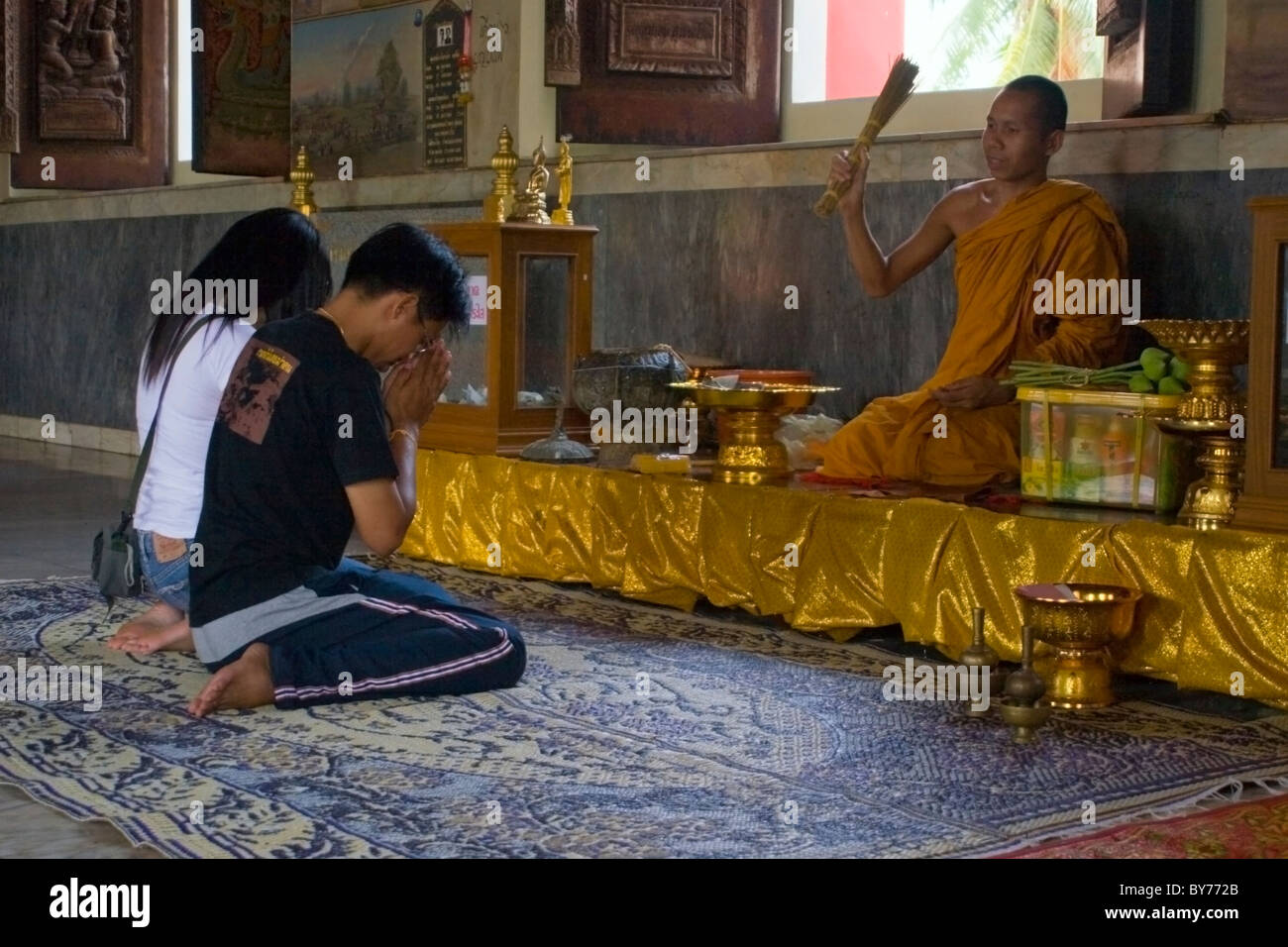 Un monje budista es la celebración de una tradicional ceremonia limosnas con dos mujeres en un hermoso templo en Nong Kai, Tailandia. Foto de stock