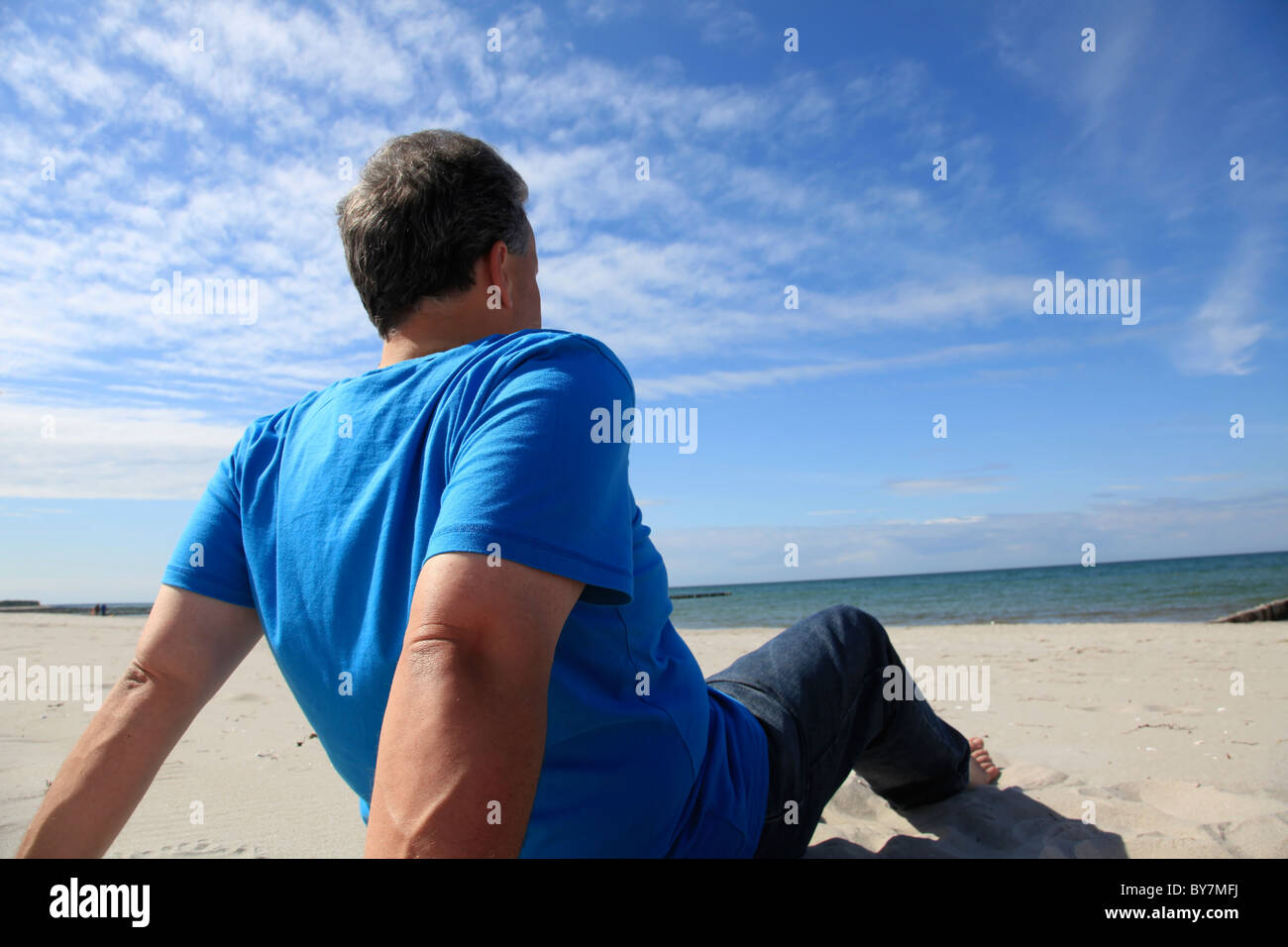 Hombre sentado en la playa Foto de stock
