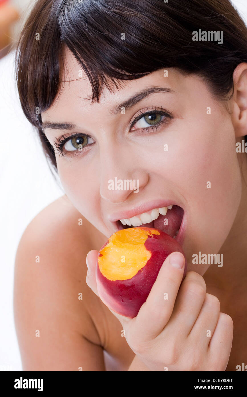 Atractiva mujer joven sonriente y nectarina fresca para comer Foto de stock