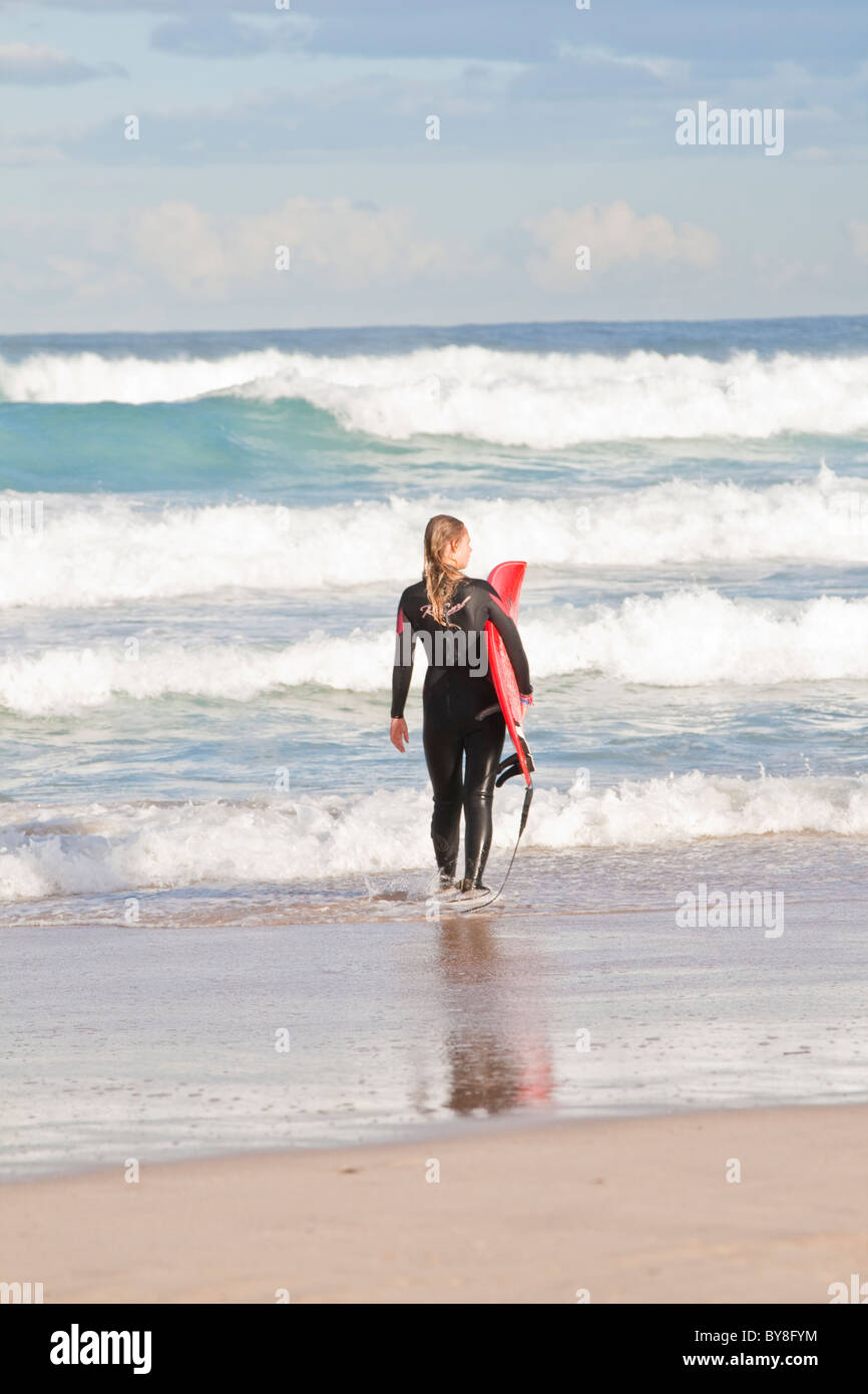 Surfer femenina entra en las olas en la playa de Bondi, en Sydney, Australia Foto de stock