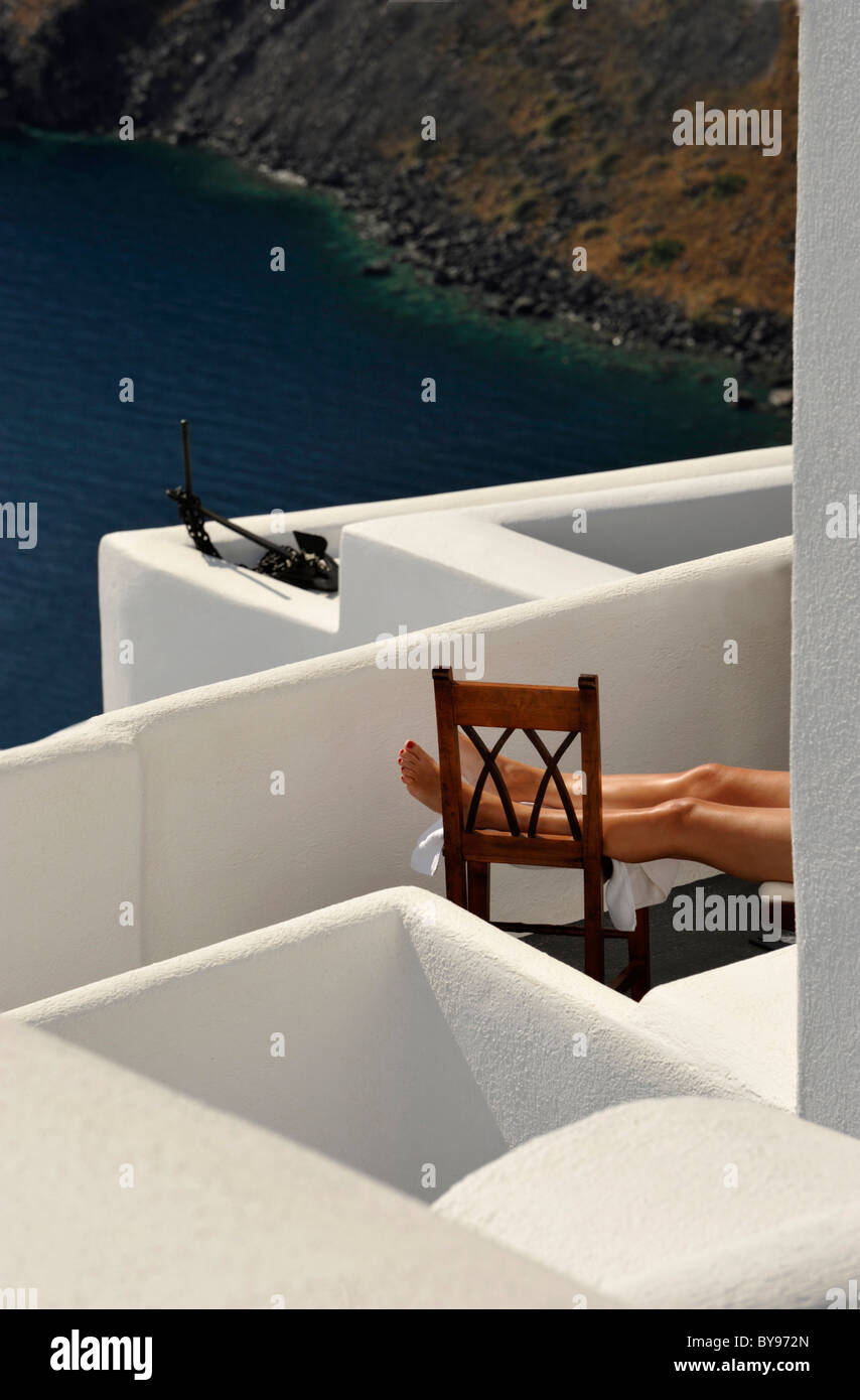 Un par de piernas bronceadas sun en un apartamento en la isla griega de Santorini, en las islas Cícladas, del mar Egeo. Foto de stock
