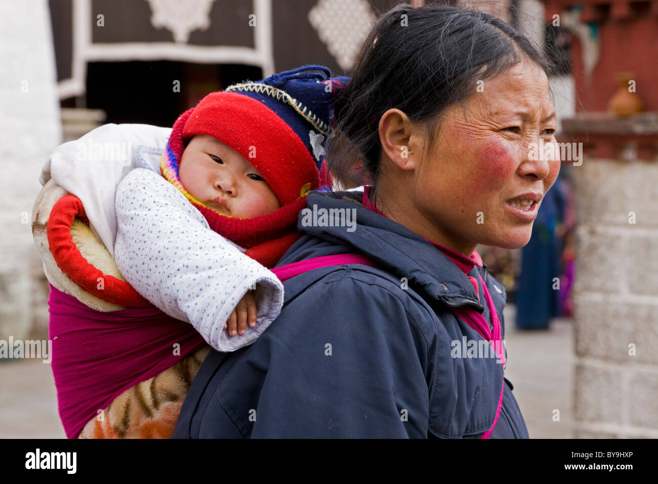 Mujer tibetana madre con bebé en papoose sobre su espalda en el Barkhor Lhasa (Tíbet). JMH4658 Foto de stock