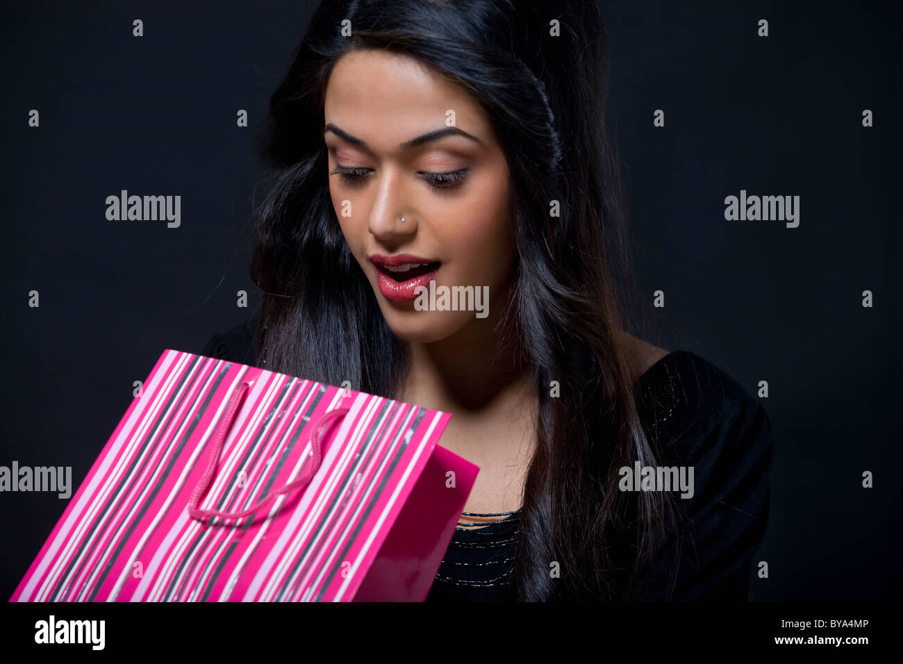 Mujer joven busca dentro de una bolsa de compras Foto de stock