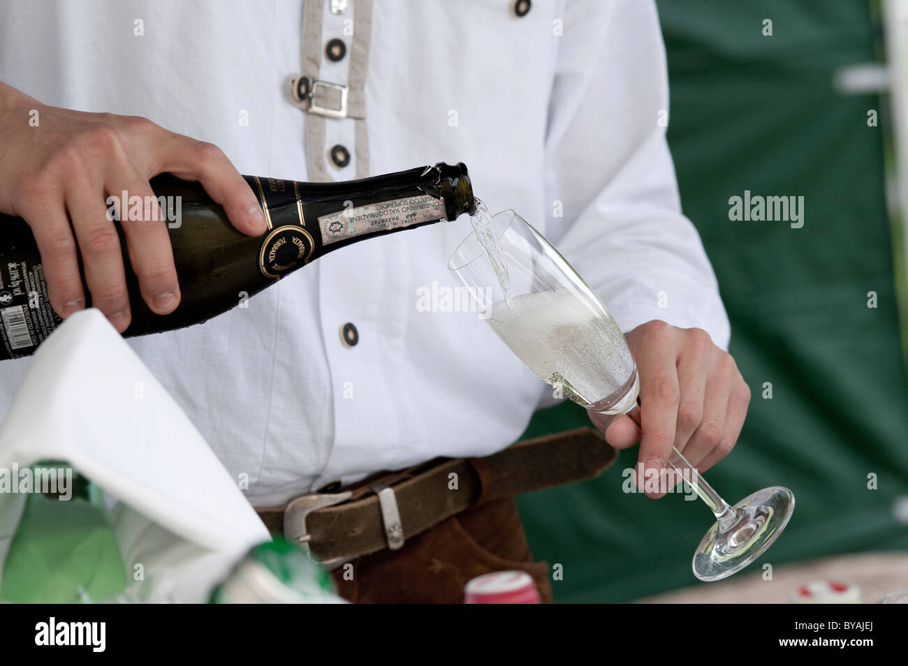Hombre vertiendo un vaso de champán o vino espumoso prosecco, close-up de manos Foto de stock