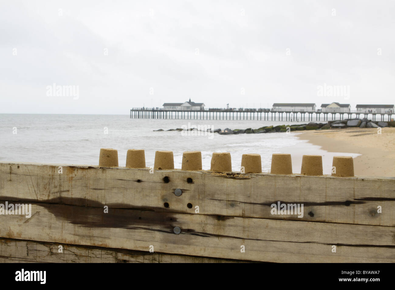 Línea de castillos de arena en la parte superior de una pared de madera en southwold, Suffolk Foto de stock