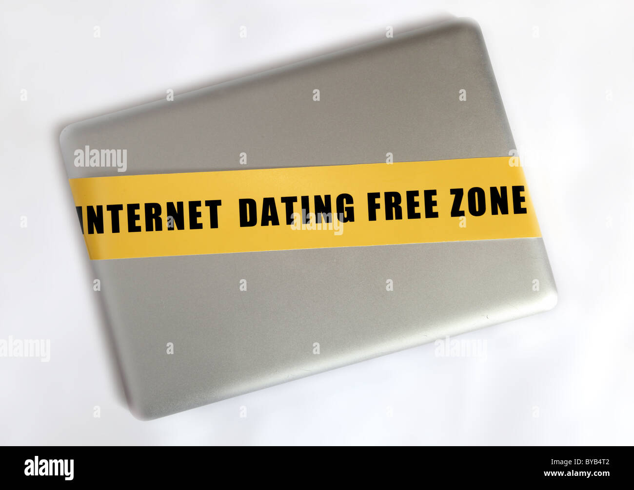 Portátil de plata con cinta amarilla con el slogan "zona franca" de citas por internet Foto de stock