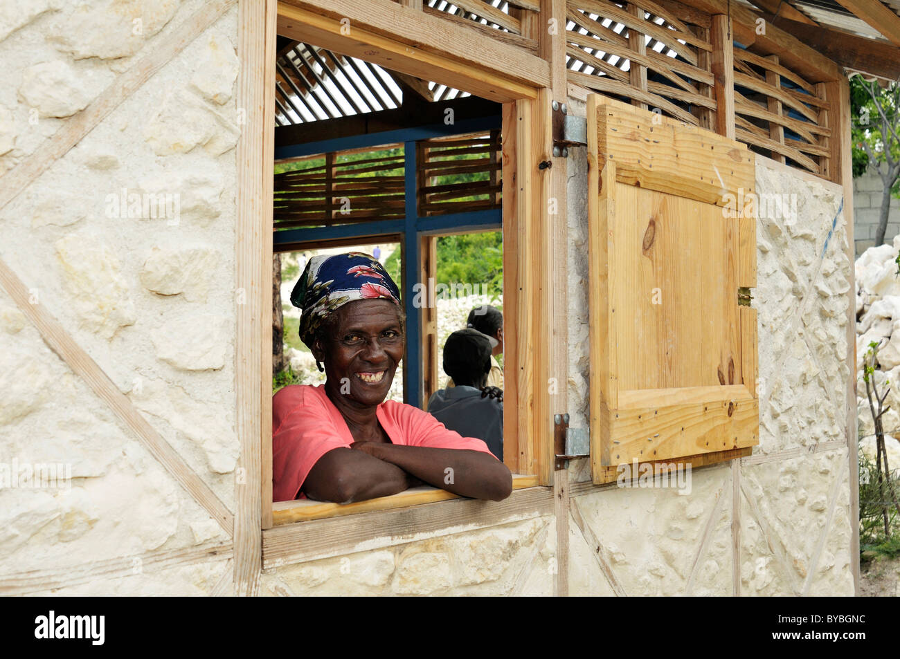 Riendo residente desde la ventana de su nueva casa segura terremoto donado por una organización alemana de ayuda, Froide River village Foto de stock