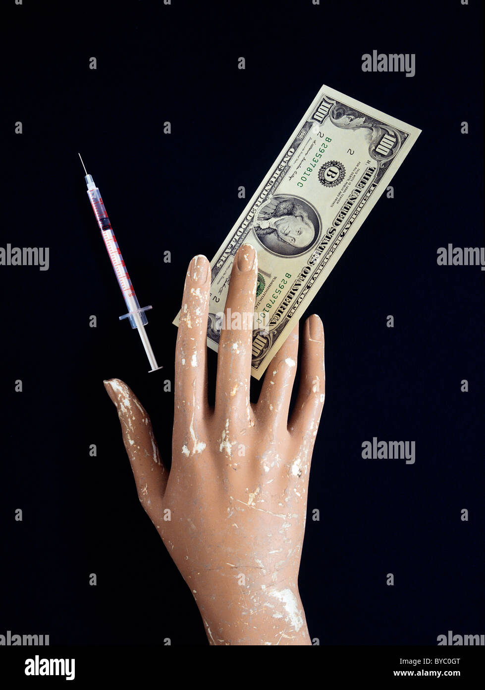 Mano ficticia con un billete de 100 dólares EE.UU. & aguja hipodérmica Foto de stock