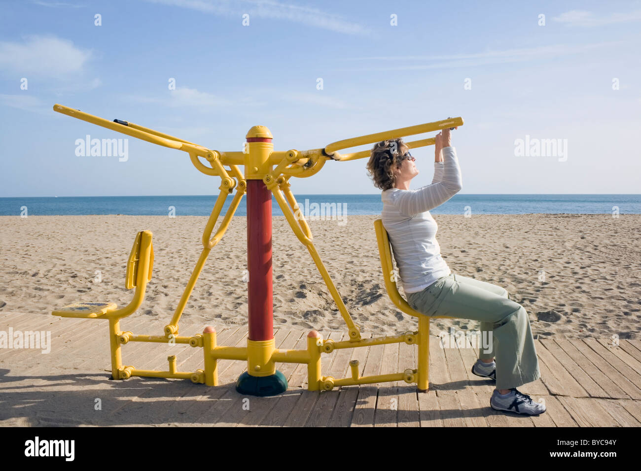 Los Boliches, Fuengirola, Costa del Sol, España. Mujer con el brazo de la máquina de ejercicio en la playa. Foto de stock