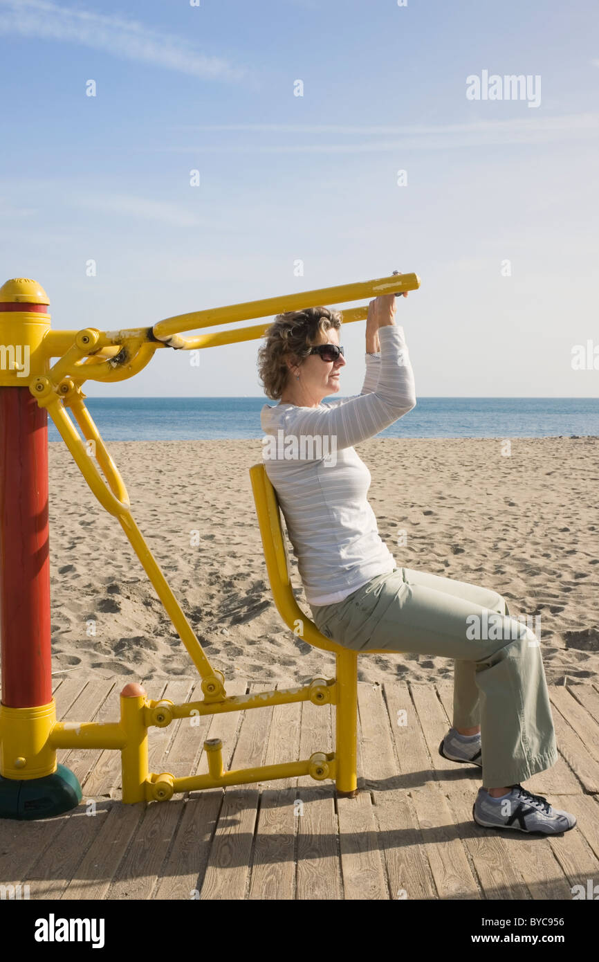 Los Boliches, Fuengirola, Costa del Sol, España. Mujer con el brazo de la máquina de ejercicio en la playa. Foto de stock