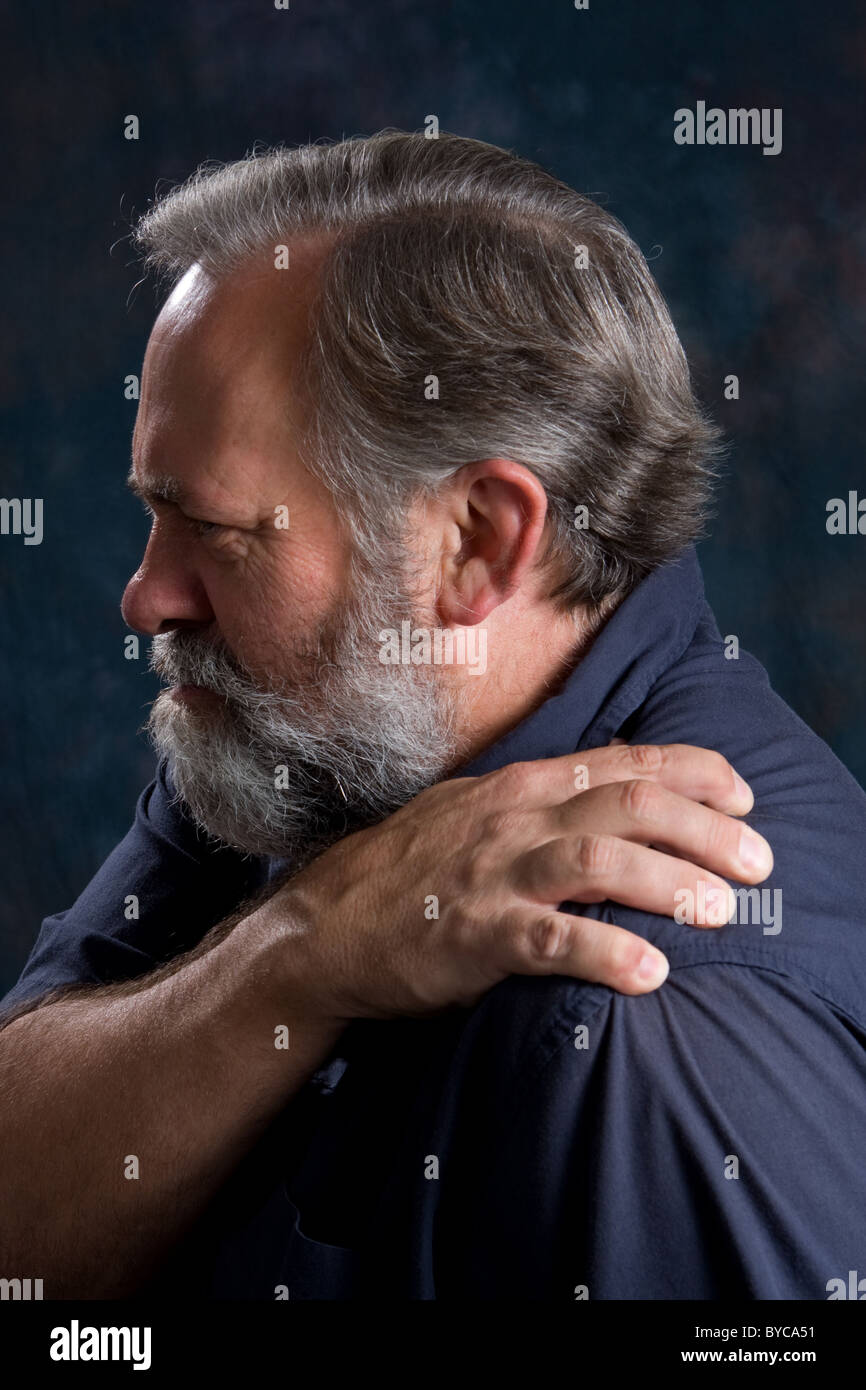 Hombre masajes su hombro doloroso. Foto de stock