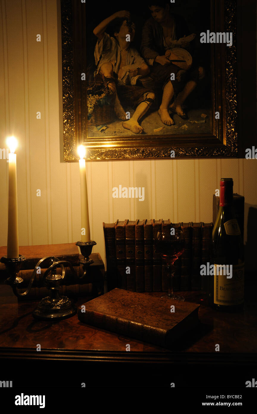 Anticuario de libros y vino iluminado por velas Foto de stock