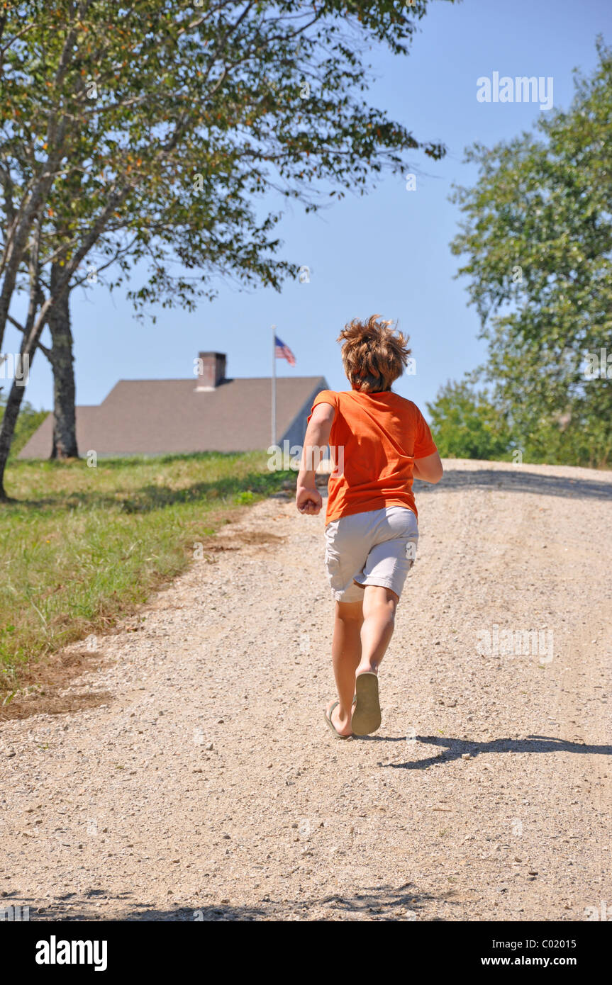 A los 12 años de edad niño corriendo cuesta arriba a casa Foto de stock