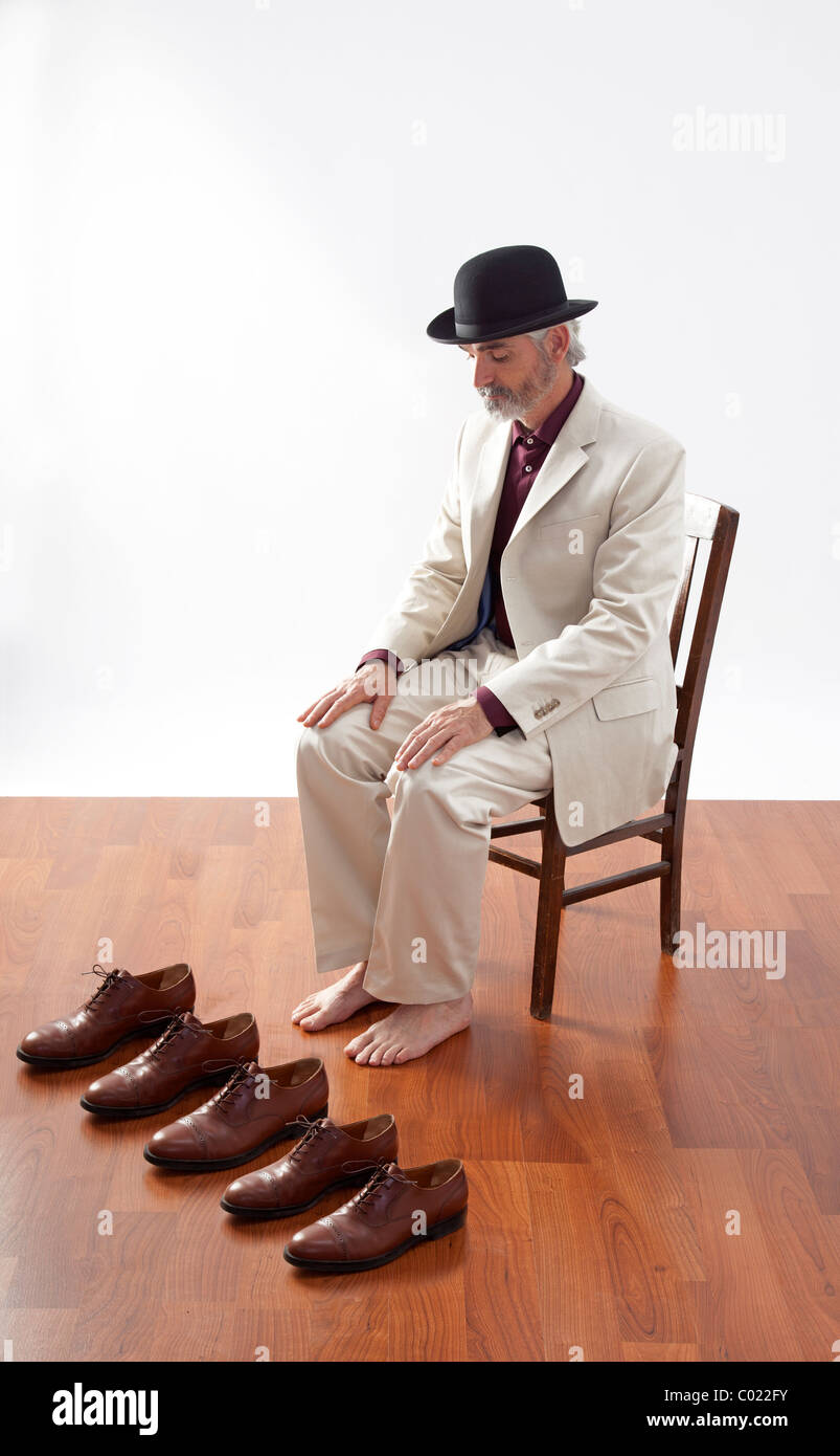 Hombre sentado con los pies descalzos detrás 5 zapatos idénticos. Foto de stock