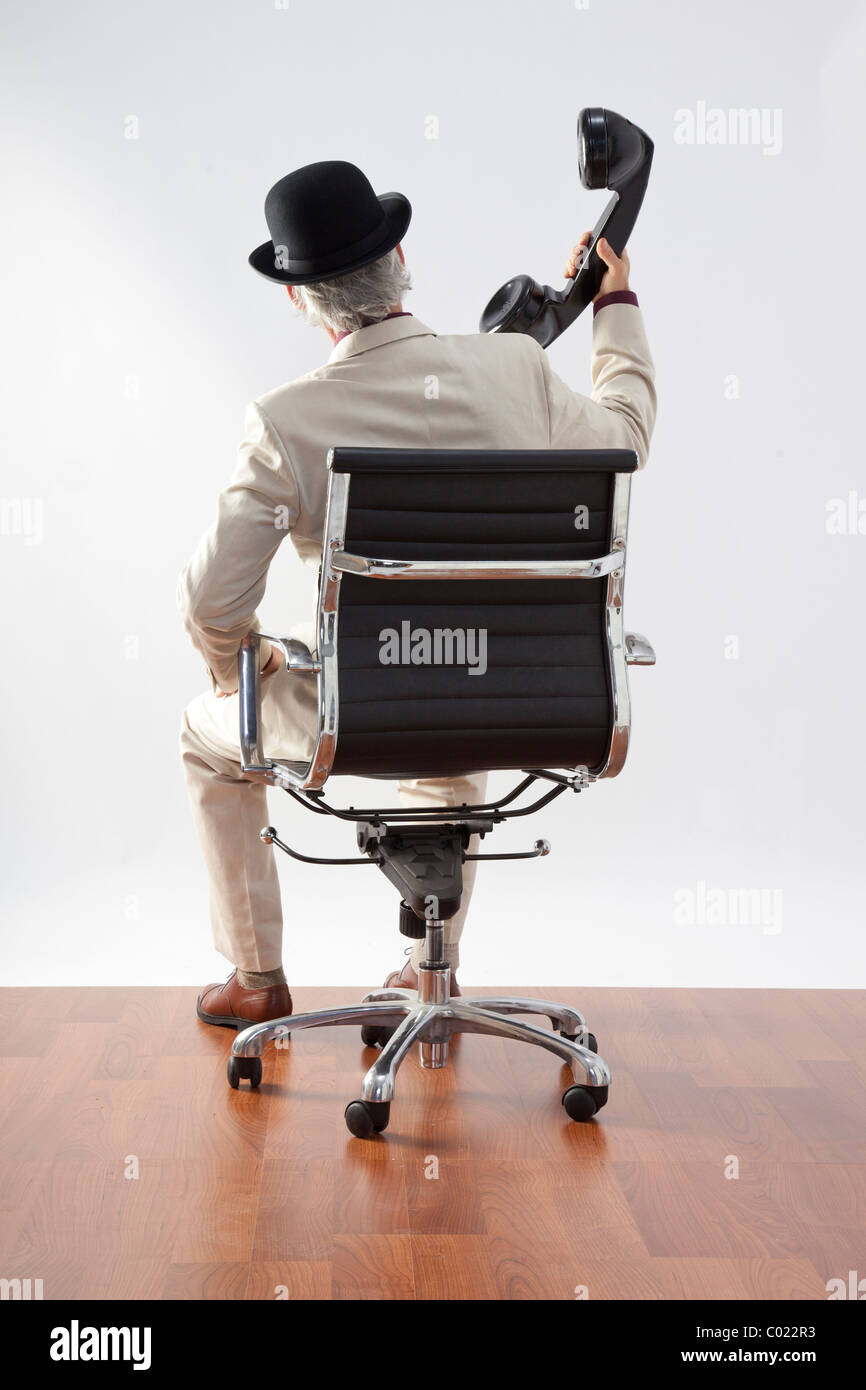 Hombre en silla gigante con receptor telefónico celebradas fuera de oreja Foto de stock