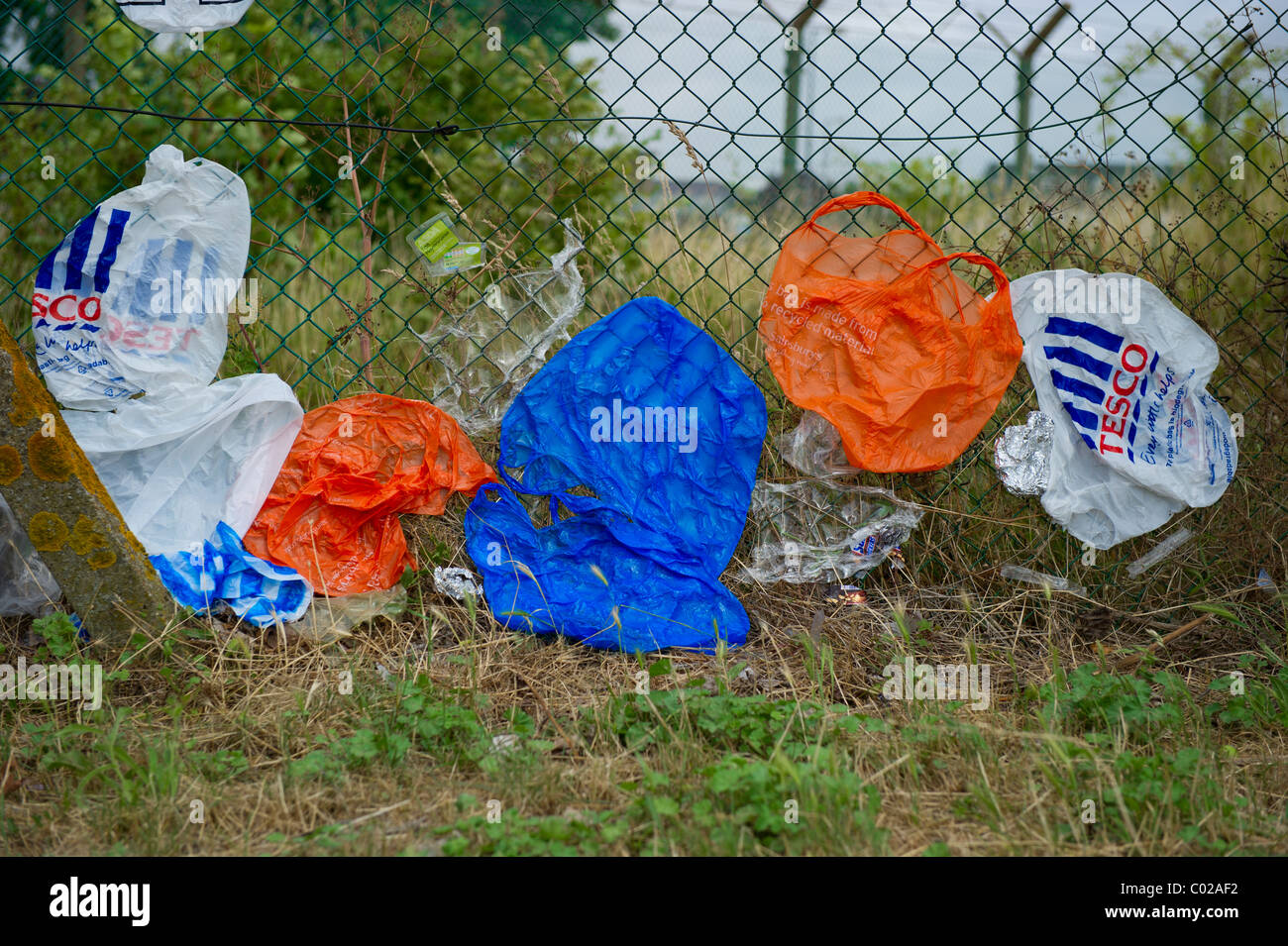 Bolsas de compras de plástico de diferentes almacenes de soplarse contra el  eslabón de la cadena esgrima en muy alto el viento Fotografía de stock -  Alamy