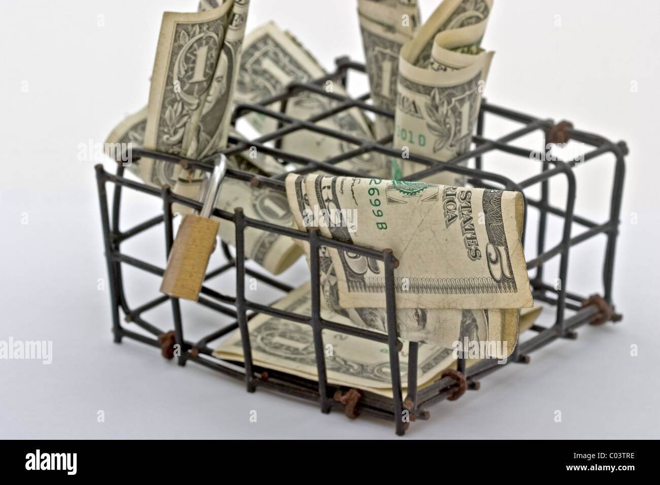 Pequeña jaula negro lleno de billetes de dólar americano con un pequeño candado en la parte superior Foto de stock