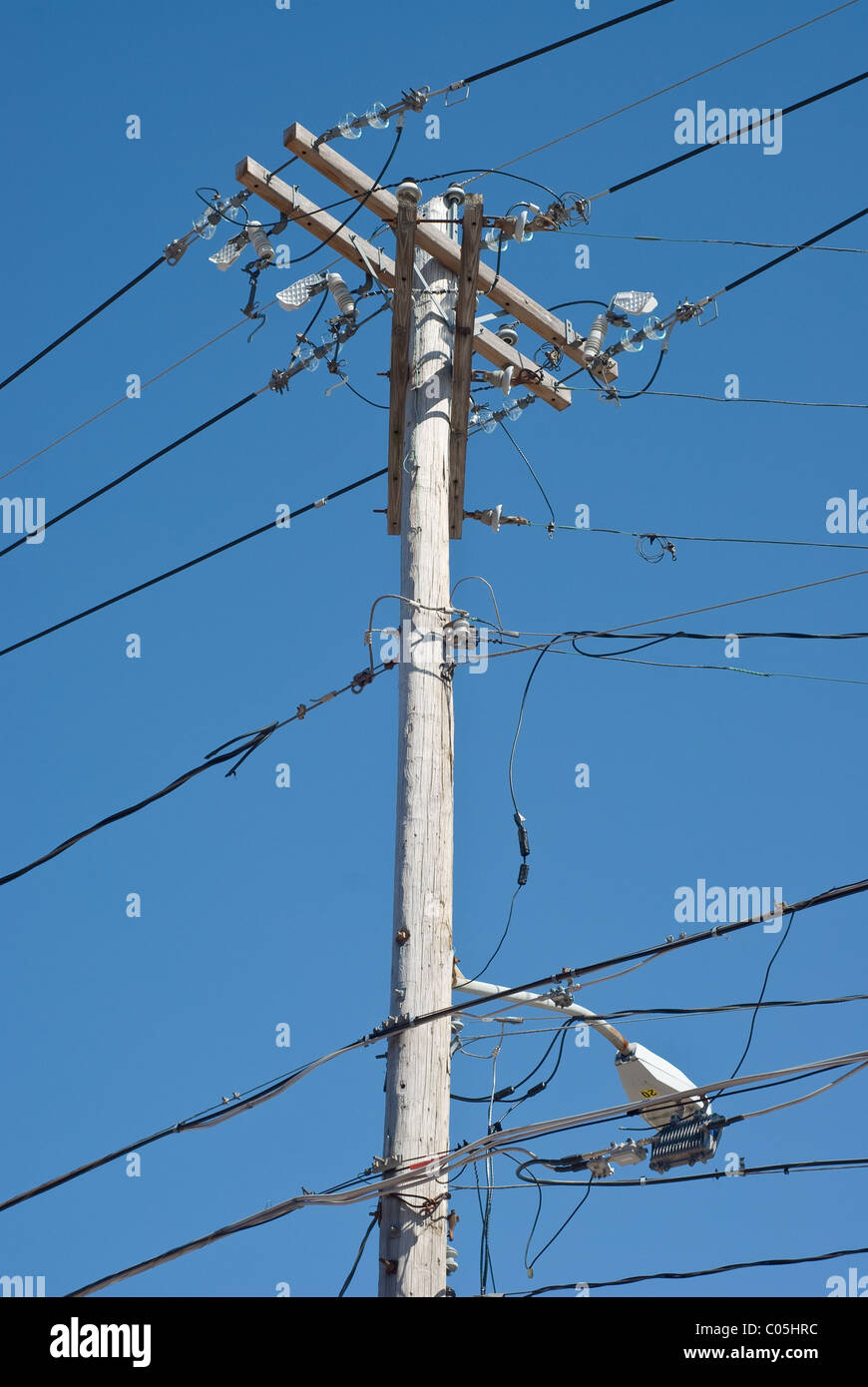 Poste telefónico de madera con líneas de transporte de energía eléctrica y la luz Foto de stock