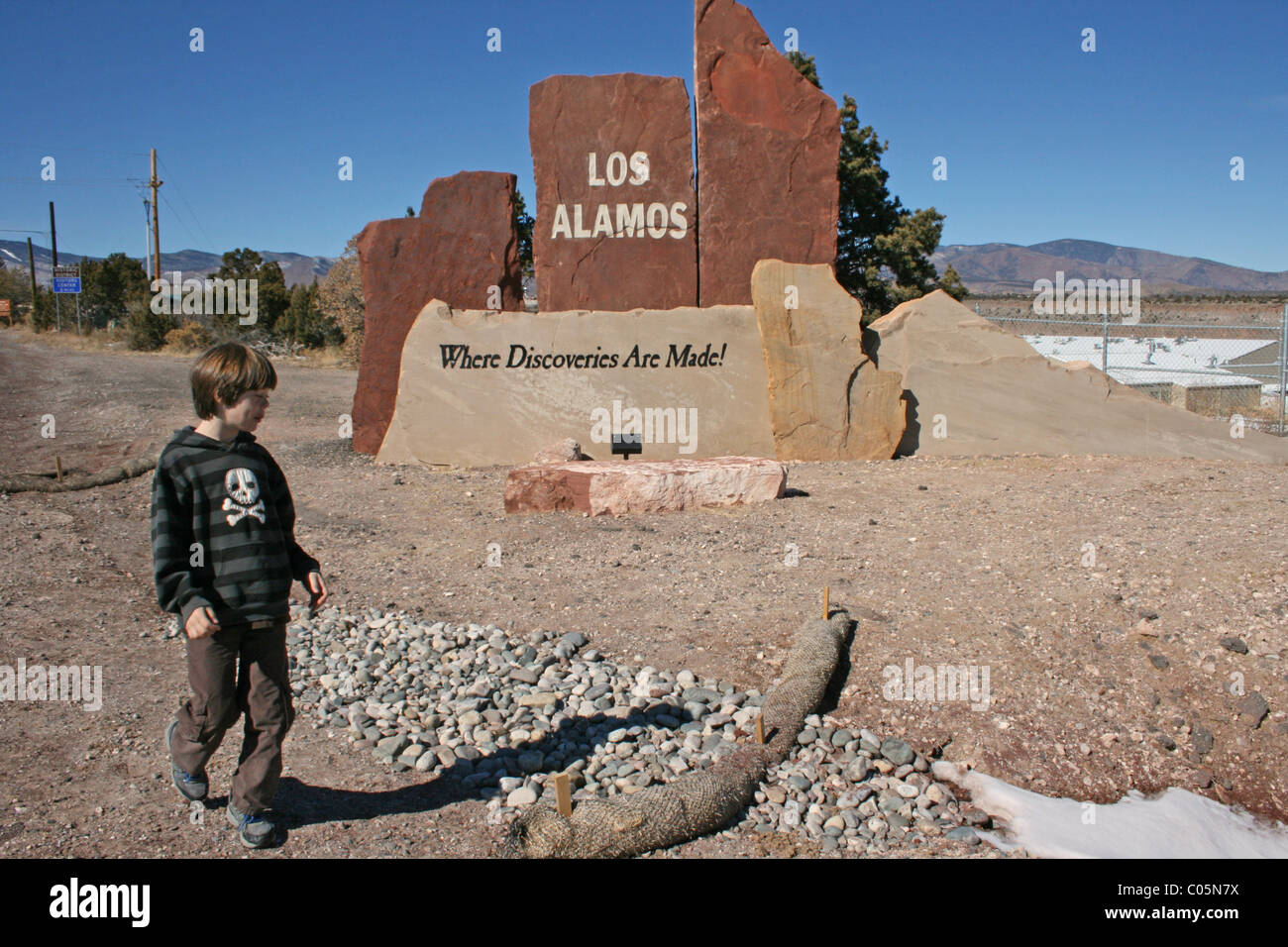 Niño caminando en Los Alamos, Nuevo México, con cartel que dice, "Los