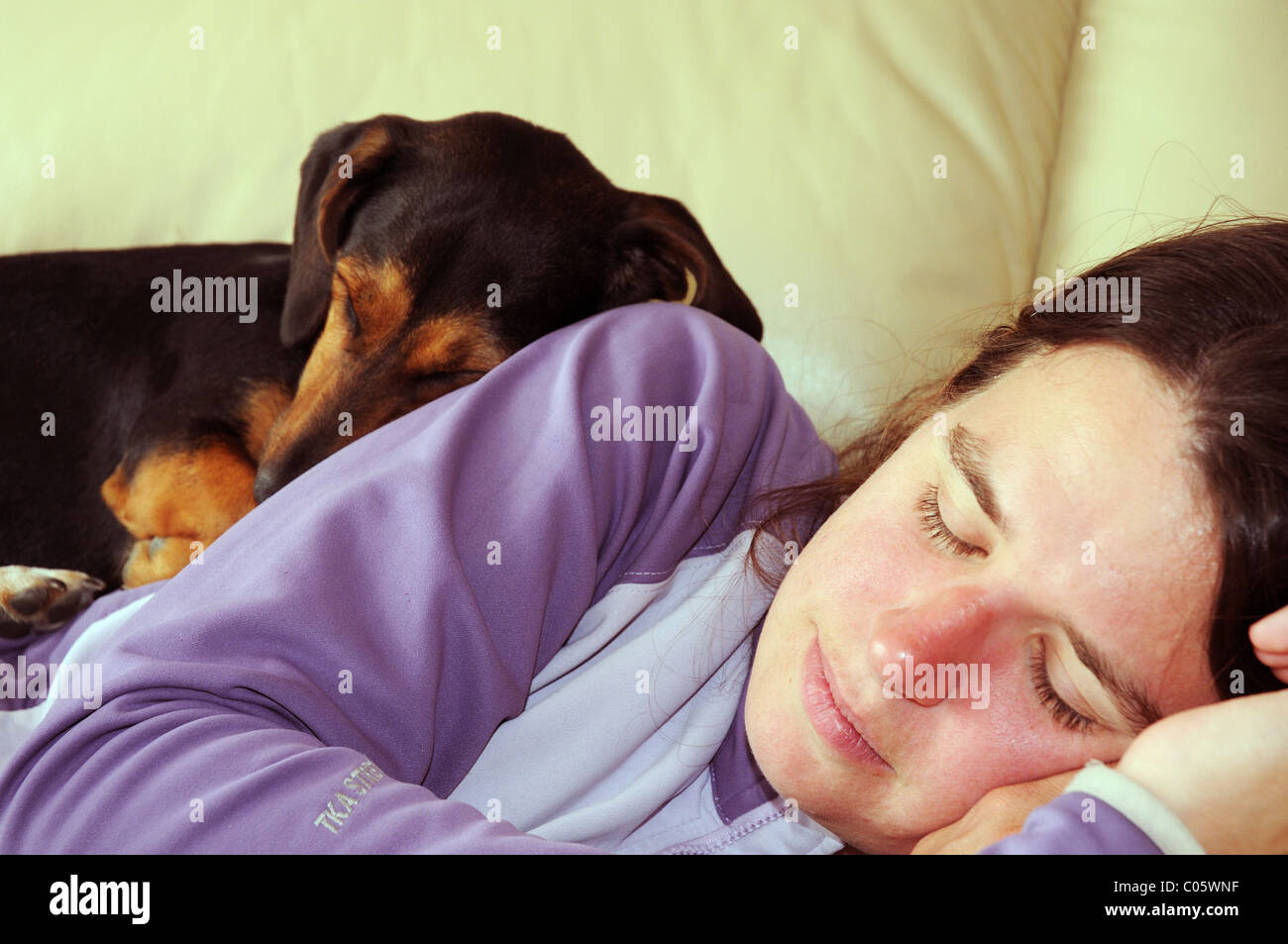 Un perro dormido acurrucados en una mujer durmiendo Foto de stock