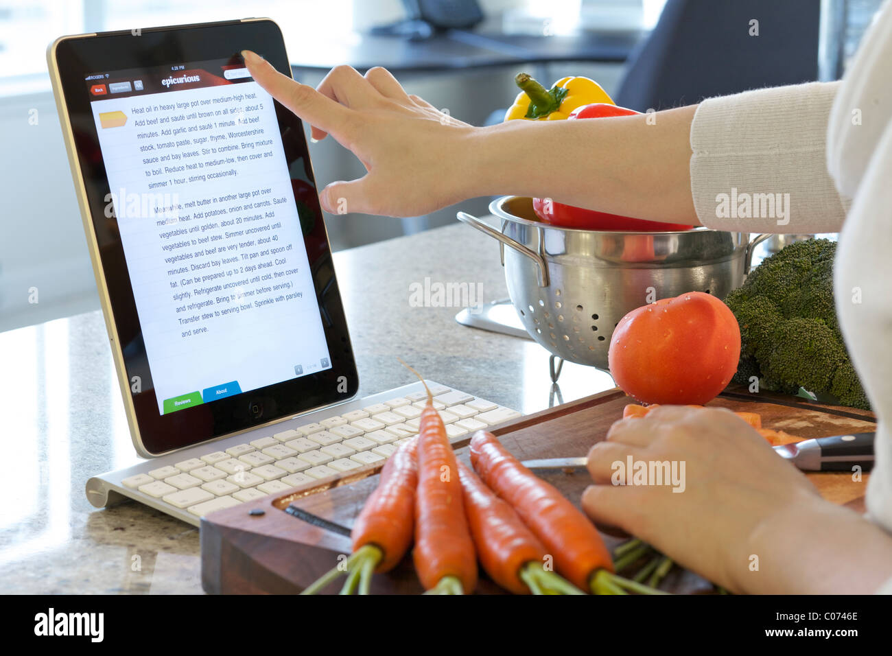 Mujer mostrando instrucciones de cocción en línea con Epicurious iPad app de cocción Foto de stock