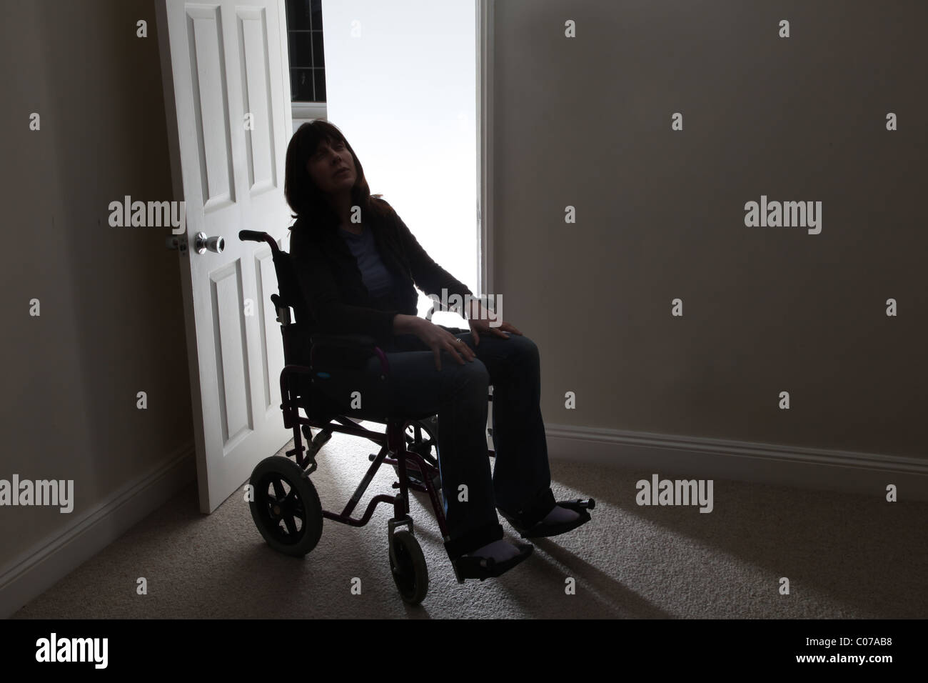 Mujer en una silla de ruedas únicamente por una puerta abierta Foto de stock
